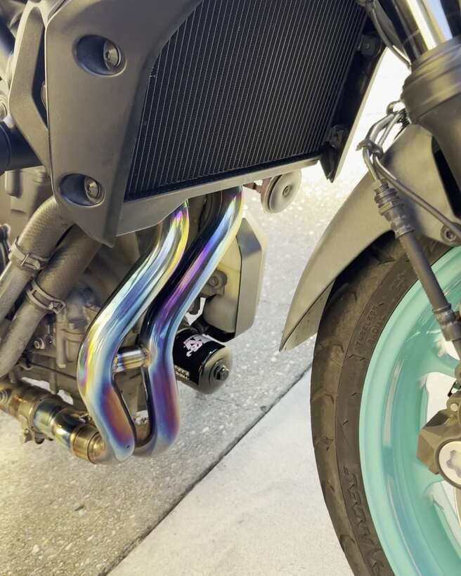 Blue titanium exhaust headers and a teal wheel after detailing