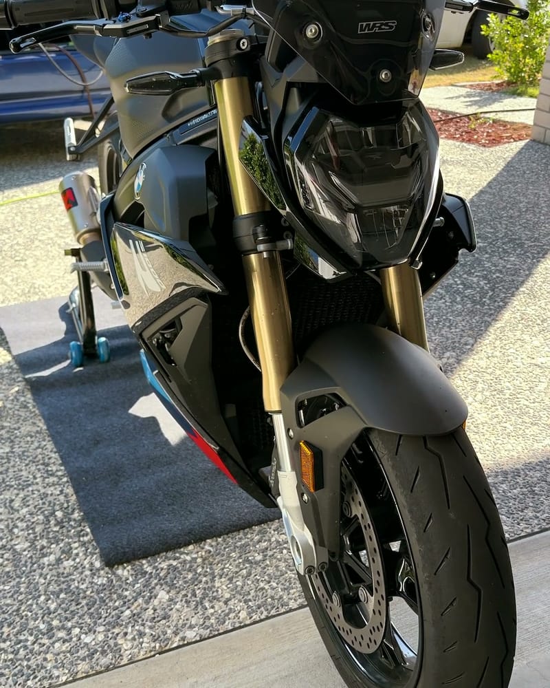 BMW S1000R after paint correction and a ceramic coating — gold forks, clean front wheel and brake discs on the driveway